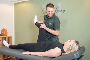 Osteopath mobilisiert Hüfte und Bein einer Patientin auf der Behandlungsliege