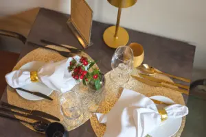 Zwei Gedecke von oben mit goldenem Besteck, Platzsets und Blumenschmuck – Tischkultur im Restaurant