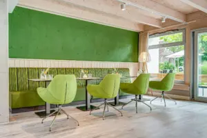 Café-Bereich einer Tagespflege mit grüner Sitzbank und hellgrünen Stühlen
