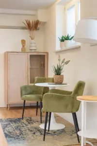 Kleine Sitzecke mit grünen Sesseln und Holzvitrine in einer Senioreneinrichtung